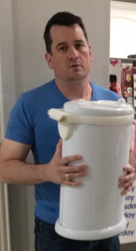 A poker face man holding a white trash bin