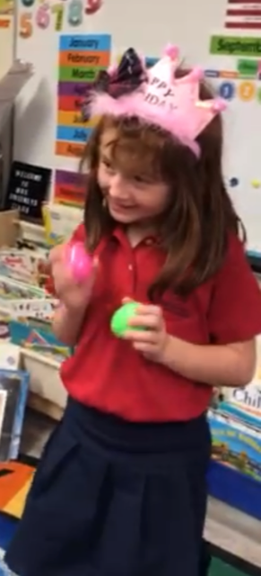A kindergartener smiling wearing her pink tiara 