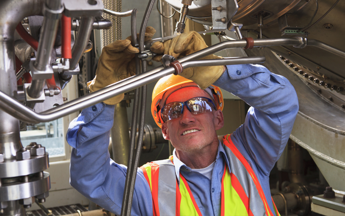 employee performing maintenance with safety goggles and safety vest