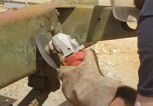 A man using a grinding wheel to take the rivet off
