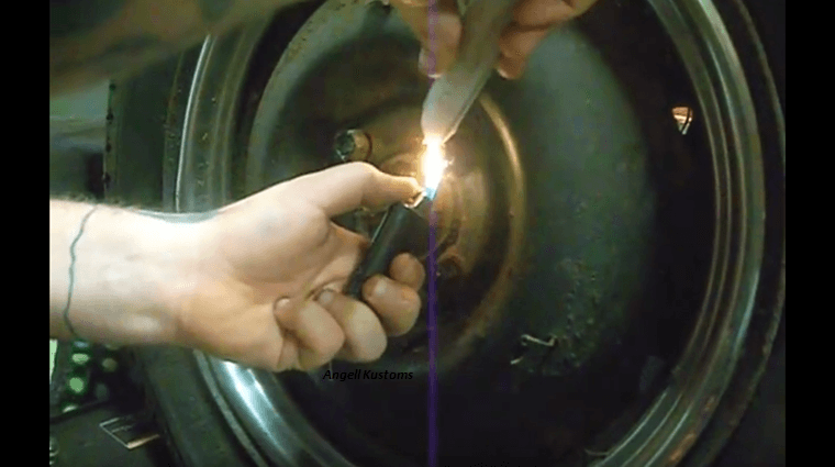 A hand lighting up a candle wax with a lighter near lug nuts