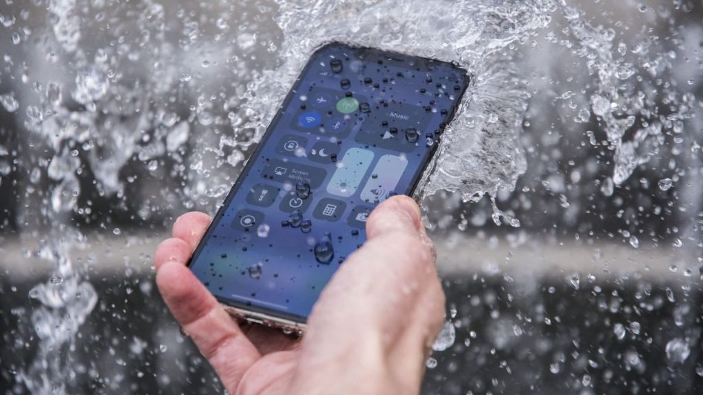 A mobile phone held by a man in rain